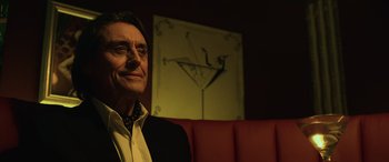 Movie still from “John Wick” (2014), directed by Chad Stahelski – An older man sitting in front of a painting; Close Up shot, Low angle