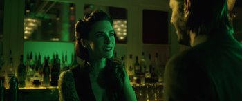 Movie still from “John Wick” (2014), directed by Chad Stahelski – A beautiful woman smiling in a green lit room; Close Up shot, Over the shoulder angle