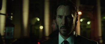 Movie still from “John Wick” (2014), directed by Chad Stahelski – A man in a suit and tie in front of lights; Close Up shot, Low angle