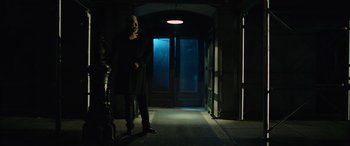Movie still from “John Wick” (2014), directed by Chad Stahelski – A man standing in a dark room next to an open door; Wide shot, Low angle