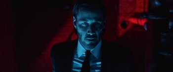 Movie still from “John Wick” (2014), directed by Chad Stahelski – A man wearing a suit and tie in a dark room; Close Up shot, Low angle