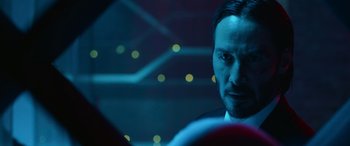 Movie still from “John Wick” (2014), directed by Chad Stahelski – A man in a suit and tie looking at the camera; Close Up shot, Over the shoulder angle