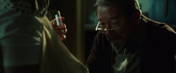 Movie still from “John Wick” (2014), directed by Chad Stahelski – An older man holding a glass of water; Close Up shot, Over the shoulder angle