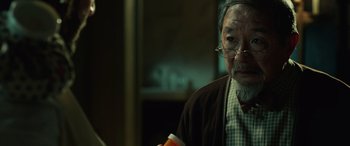Movie still from “John Wick” (2014), directed by Chad Stahelski – An older man wearing glasses is holding a coffee cup; Close Up shot, Over the shoulder angle