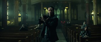 Movie still from “John Wick” (2014), directed by Chad Stahelski – A man holding a camera in a dark room; Medium shot, Low angle