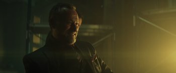 Movie still from “John Wick” (2014), directed by Chad Stahelski – A man with a goatee is smiling in the dark; Close Up shot, Over the shoulder angle