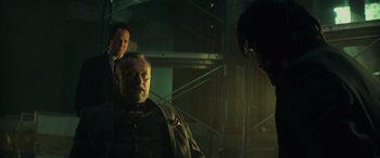 Movie still from “John Wick” (2014), directed by Chad Stahelski – A group of people standing around in a room; Medium shot, Over the shoulder angle