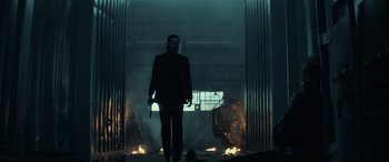 Movie still from “John Wick” (2014), directed by Chad Stahelski – A man holding a gun while standing next to a fire pit; Wide shot, Low angle