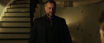 Movie still from “John Wick” (2014), directed by Chad Stahelski – A man in a suit and tie standing in a room; Medium shot, Low angle