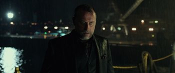 Movie still from “John Wick” (2014), directed by Chad Stahelski – A man in a suit and tie standing in front of lights; Close Up shot, Over the shoulder angle