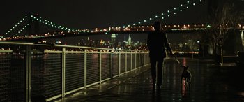 Movie still from “John Wick” (2014), directed by Chad Stahelski – A person walking on a bridge at night; Wide shot, Over the shoulder angle