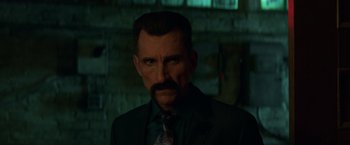 Movie still from “John Wick: Chapter 2” (2017), directed by Chad Stahelski – A man in a suit and tie with a mustache; Close Up shot, Over the shoulder angle