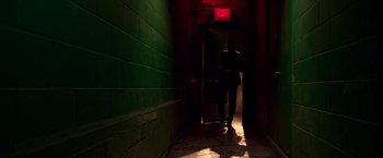 Movie still from “John Wick: Chapter 2” (2017), directed by Chad Stahelski – A person standing in a dark hallway with a green wall; Wide shot, Low angle
