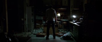 Movie still from “John Wick: Chapter 2” (2017), directed by Chad Stahelski – A man standing in a room with a box of apples; Wide shot, Low angle