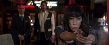Movie still from “John Wick: Chapter 2” (2017), directed by Chad Stahelski – A woman pointing at the camera while a man stands behind her; Medium shot, Over the shoulder angle