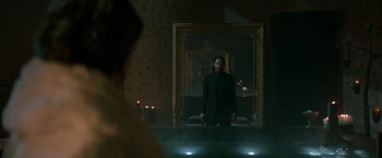 Movie still from “John Wick: Chapter 2” (2017), directed by Chad Stahelski – A man standing in front of a mirror in a dark room; Medium shot, Over the shoulder angle