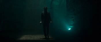 Movie still from “John Wick: Chapter 2” (2017), directed by Chad Stahelski – A man in a suit and mask walking through a dark tunnel; Wide shot, Low angle