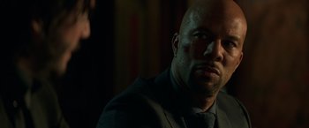 Movie still from “John Wick: Chapter 2” (2017), directed by Chad Stahelski – A man with a shaved head is looking at the camera; Close Up shot, Over the shoulder angle