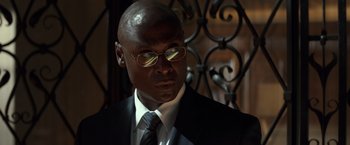 Movie still from “John Wick: Chapter 2” (2017), directed by Chad Stahelski – A man in a suit and tie wearing glasses; Close Up shot, Low angle