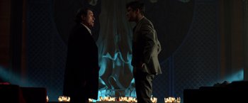 Movie still from “John Wick: Chapter 2” (2017), directed by Chad Stahelski – Two men standing next to each other in front of candles; Medium shot, Over the shoulder angle