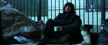 Movie still from “John Wick: Chapter 2” (2017), directed by Chad Stahelski – A man sitting on the ground holding a mug; Medium shot, Low angle