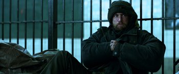 Movie still from “John Wick: Chapter 2” (2017), directed by Chad Stahelski – A man sitting in a jail cell with his arms crossed; Medium shot, Low angle