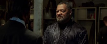 Movie still from “John Wick: Chapter 2” (2017), directed by Chad Stahelski – A man with a beard and a black and white polka dot shirt; Close Up shot, Over the shoulder angle