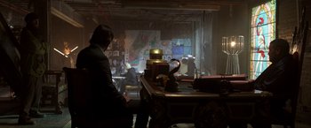 Movie still from “John Wick: Chapter 2” (2017), directed by Chad Stahelski – A man sitting at a table in front of a painting; Wide shot, Over the shoulder angle