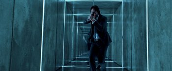Movie still from “John Wick: Chapter 2” (2017), directed by Chad Stahelski – A man holding a gun in a dark room; Medium shot, Low angle