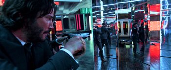 Movie still from “John Wick: Chapter 2” (2017), directed by Chad Stahelski – A man holding a gun in front of two other men; Medium shot, Over the shoulder angle