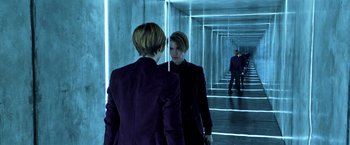 Movie still from “John Wick: Chapter 2” (2017), directed by Chad Stahelski – A woman in a purple jacket looking at herself in a mirror; Medium shot, Over the shoulder angle