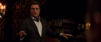 Movie still from “John Wick: Chapter 2” (2017), directed by Chad Stahelski – A man in a suit and tie standing in front of a bar; Close Up shot, Over the shoulder angle