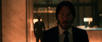 Movie still from “John Wick: Chapter 2” (2017), directed by Chad Stahelski – A man in a suit and tie with blood all over his face; Medium shot, Low angle