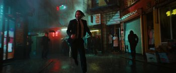 Movie still from “John Wick: Chapter 3 - Parabellum” (2019), directed by Chad Stahelski – A man that is running in the rain; Wide shot, Low angle
