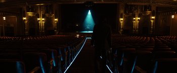 Movie still from “John Wick: Chapter 3 - Parabellum” (2019), directed by Chad Stahelski – A man standing in a theater with a light shining on him; Extreme Wide shot, Low angle