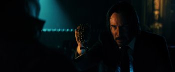 Movie still from “John Wick: Chapter 3 - Parabellum” (2019), directed by Chad Stahelski – A man in a black suit holding a chain in a dark room; Close Up shot, Over the shoulder angle