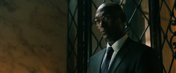 Movie still from “John Wick: Chapter 3 - Parabellum” (2019), directed by Chad Stahelski – A man in a suit and tie standing in front of a metal gate; Close Up shot, Low angle