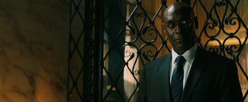 Movie still from “John Wick: Chapter 3 - Parabellum” (2019), directed by Chad Stahelski – A man in a suit and tie standing in front of an iron gate; Close Up shot, Low angle