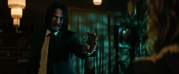 Movie still from “John Wick: Chapter 3 - Parabellum” (2019), directed by Chad Stahelski – A man in a black suit holding something in his hand; Medium shot, Over the shoulder angle