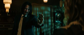 Movie still from “John Wick: Chapter 3 - Parabellum” (2019), directed by Chad Stahelski – A man holding a glass in his hand; Medium shot, Over the shoulder angle