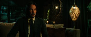 Movie still from “John Wick: Chapter 3 - Parabellum” (2019), directed by Chad Stahelski – A man in a suit sitting in front of a mirror; Medium shot, Over the shoulder angle
