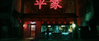 Movie still from “John Wick: Chapter 3 - Parabellum” (2019), directed by Chad Stahelski – A person standing in front of an asian restaurant at night; Extreme Wide shot, Low angle