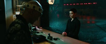 Movie still from “John Wick: Chapter 3 - Parabellum” (2019), directed by Chad Stahelski – A man sitting at a table in front of another man; Medium shot, Over the shoulder angle