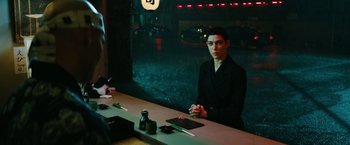 Movie still from “John Wick: Chapter 3 - Parabellum” (2019), directed by Chad Stahelski – A man sitting at a table in front of a window; Medium shot, Over the shoulder angle