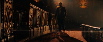 Movie still from “John Wick: Chapter 3 - Parabellum” (2019), directed by Chad Stahelski – A man standing next to a railing in a dark room; Wide shot, Low angle