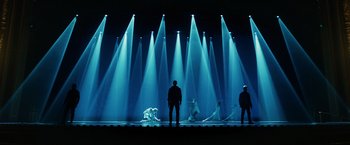 Movie still from “John Wick: Chapter 3 - Parabellum” (2019), directed by Chad Stahelski – A group of people standing on a stage in front of lights; Extreme Wide shot, Low angle