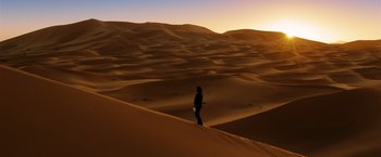 Movie still from “John Wick: Chapter 3 - Parabellum” (2019), directed by Chad Stahelski – A person standing on top of a sand dune at sunset; Extreme Wide shot, High angle