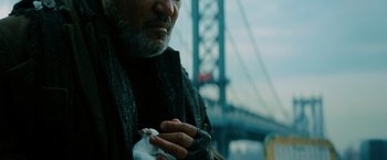 Movie still from “John Wick: Chapter 3 - Parabellum” (2019), directed by Chad Stahelski – A man holding a bird in front of a bridge; Close Up shot, Low angle