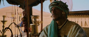 Movie still from “John Wick: Chapter 3 - Parabellum” (2019), directed by Chad Stahelski – A man in a turban and a turban stands in front of sand dunes; Close Up shot, Low angle