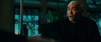 Movie still from “John Wick: Chapter 3 - Parabellum” (2019), directed by Chad Stahelski – A man sitting on top of a couch in a living room; Close Up shot, Over the shoulder angle